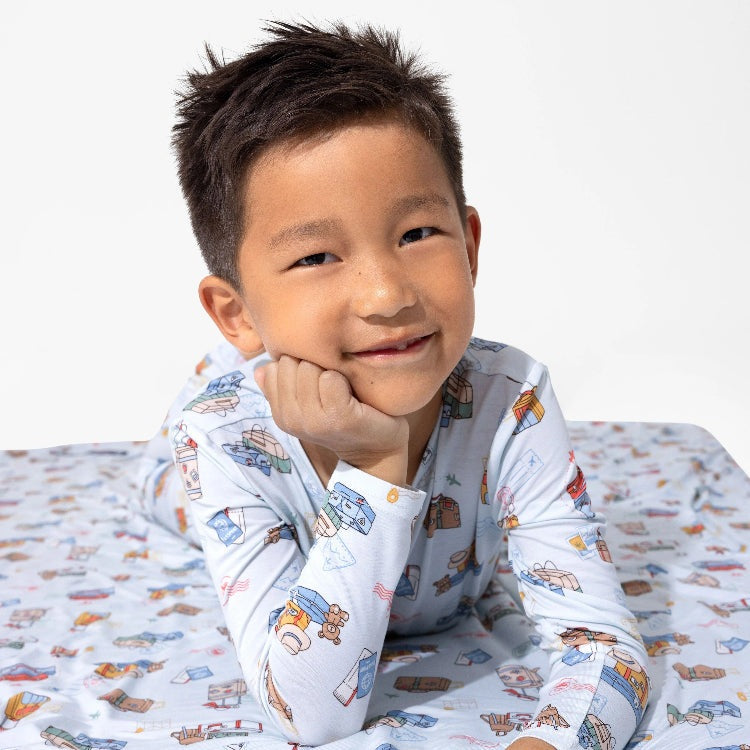 Bellabu Bear Bamboo Kids Pajamas Vintage Suitcases; cheerful boy lounging in light-blue pajamas with suitcase print.