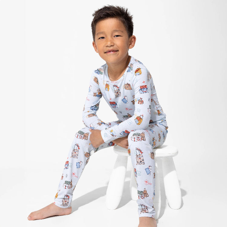 Bellabu Bear Bamboo Kids Pajamas Vintage Suitcases, light blue print; boy sits barefoot on a white stool.