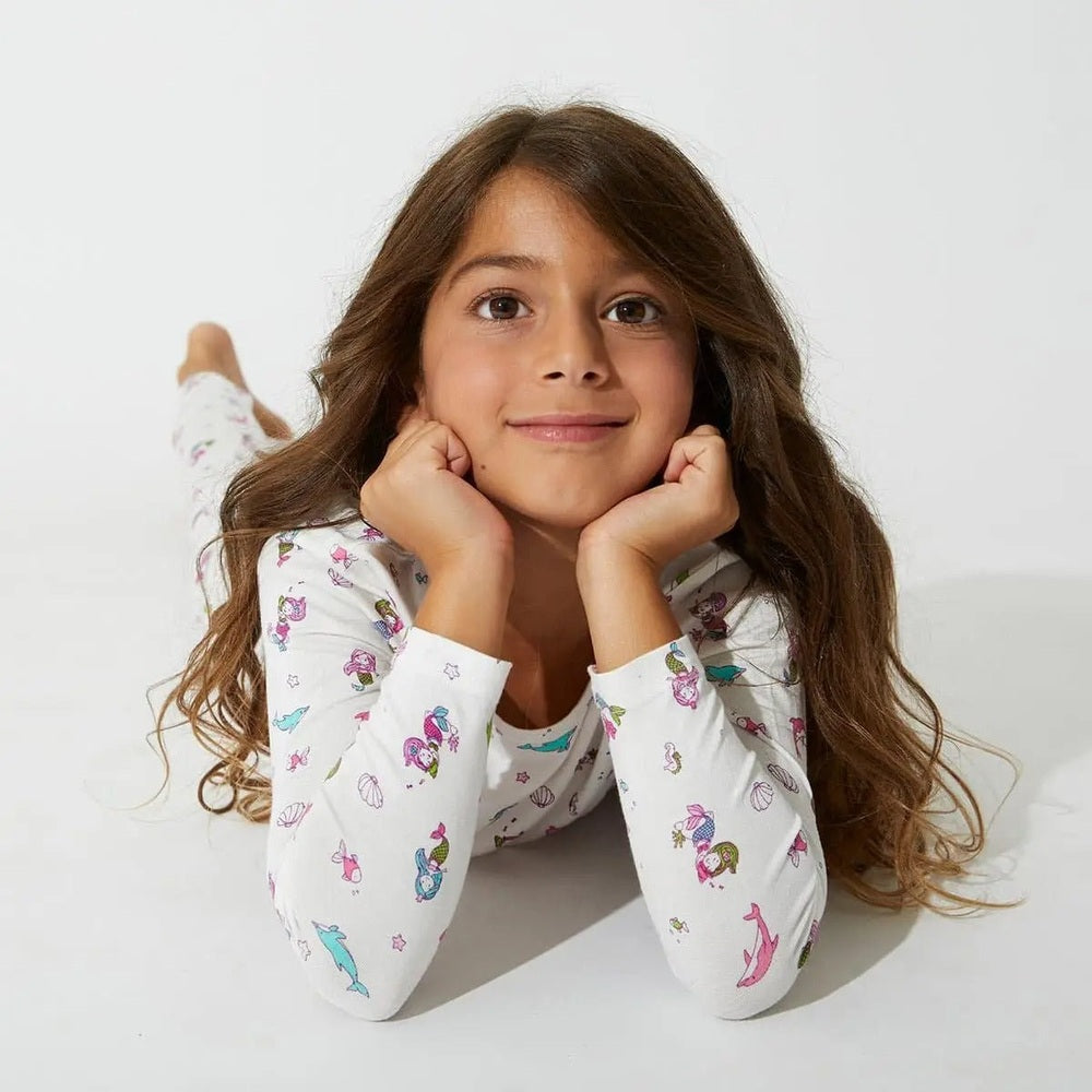 Bellabu Bear Bamboo Kids Pajamas Mermaid, white bamboo fabric with colorful mermaids, girl lying on stomach smiling.