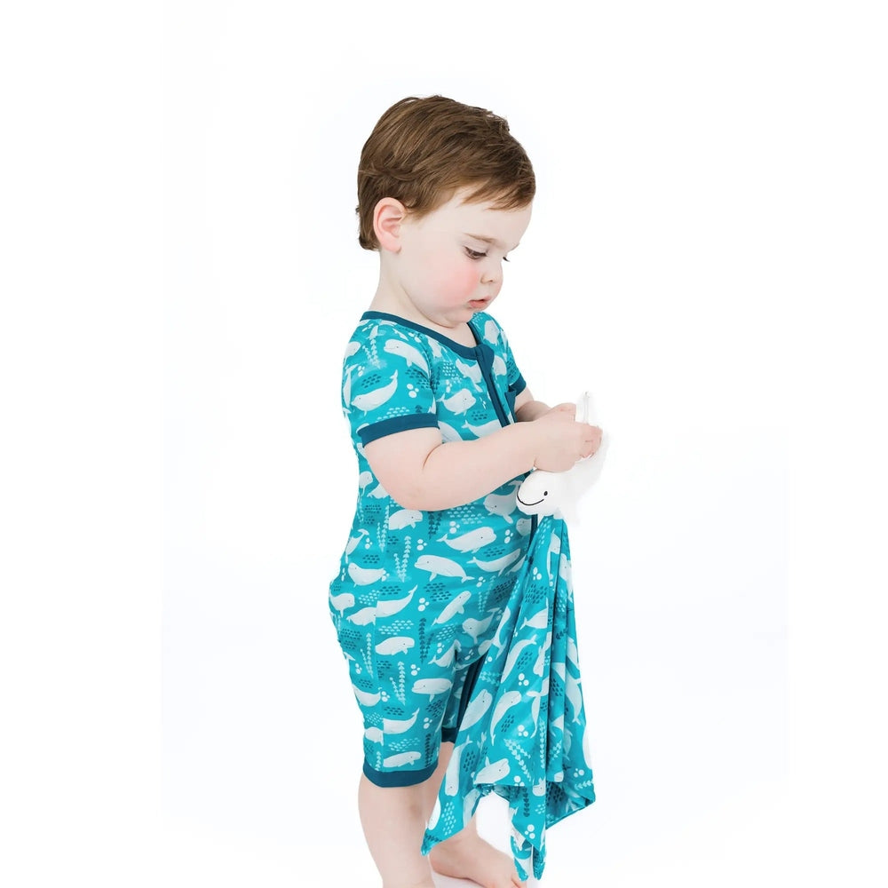 Child wearing a teal swim cover-up with whale pattern on a white background