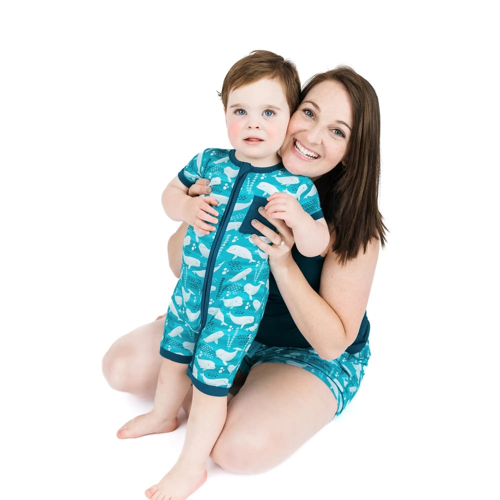 Woman and child wearing matching blue swim suits with white patterns on a white background