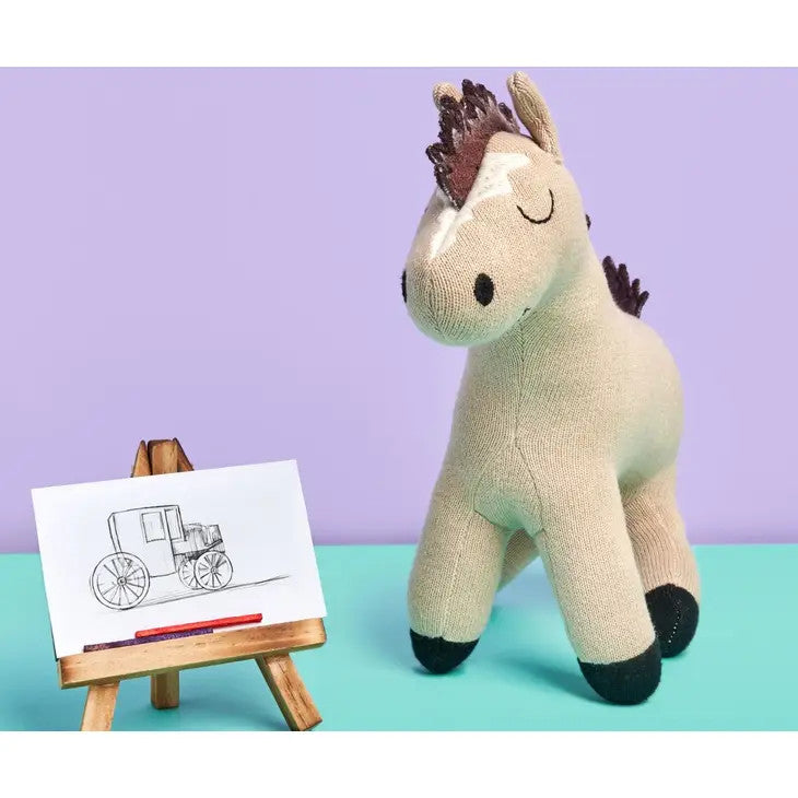Best Years organic cotton horse plush toy in beige and mint, knitted fabric, shown beside a small easel with sketch.