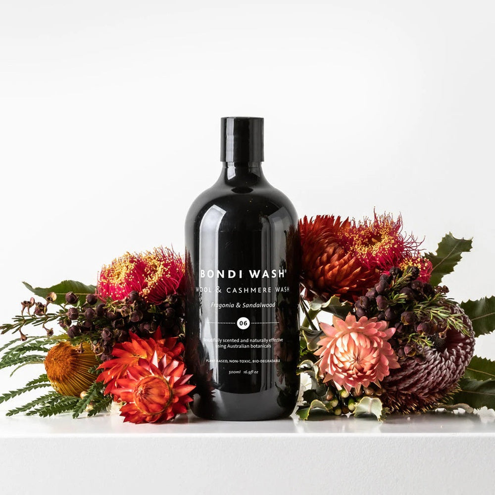 Bondi Wash Wool & Cashmere Wash Fragonia & Sandalwood 500 ml bottle with black packaging and floral arrangement