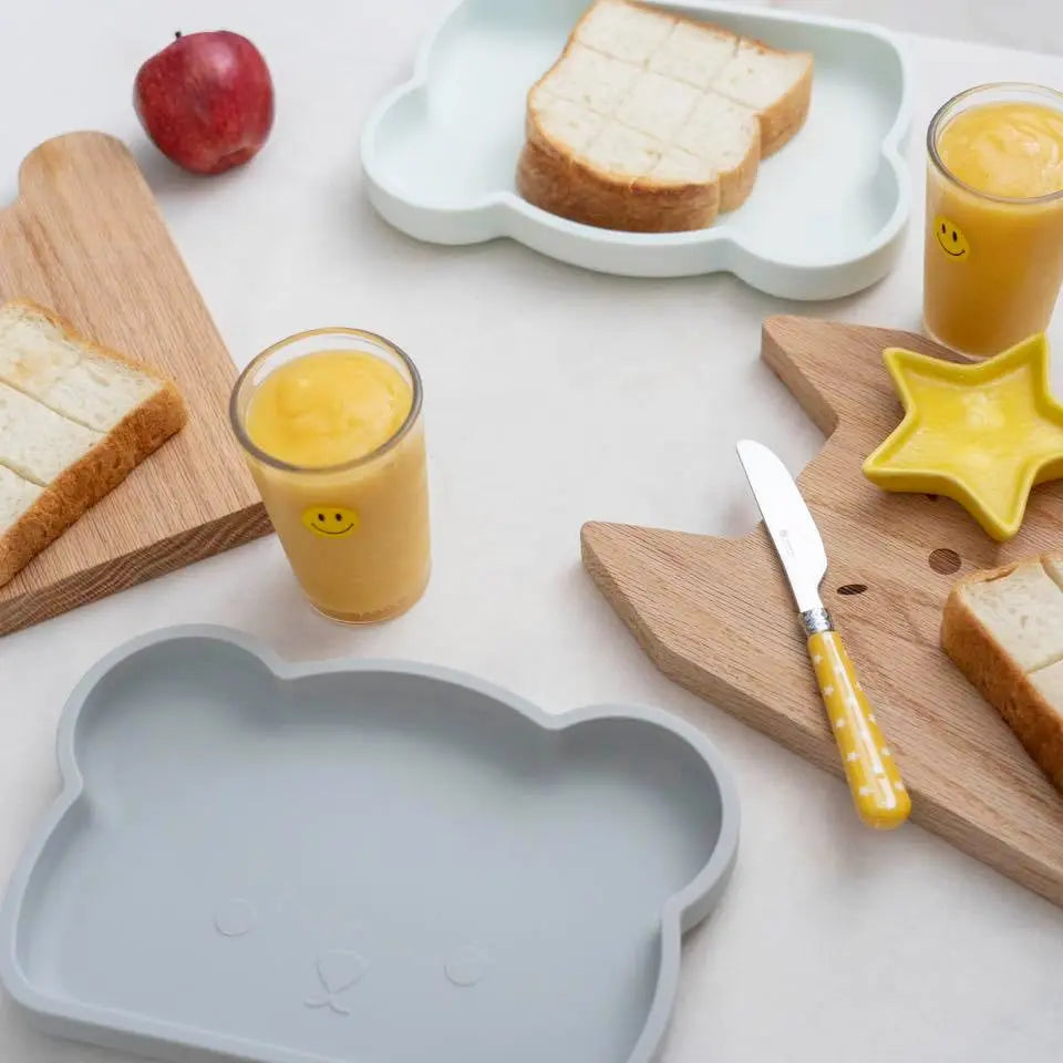 Bopomofo Bear Silicone Plate, bear-shaped gray tray shown with toast, juice, and kid-friendly utensils in a cheerful breakfast scene.