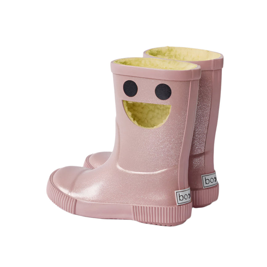 Boxbo Wistiti fleece-lined rainboots glitter pink pair, showing yellow plush lining and smiley-face cutouts.