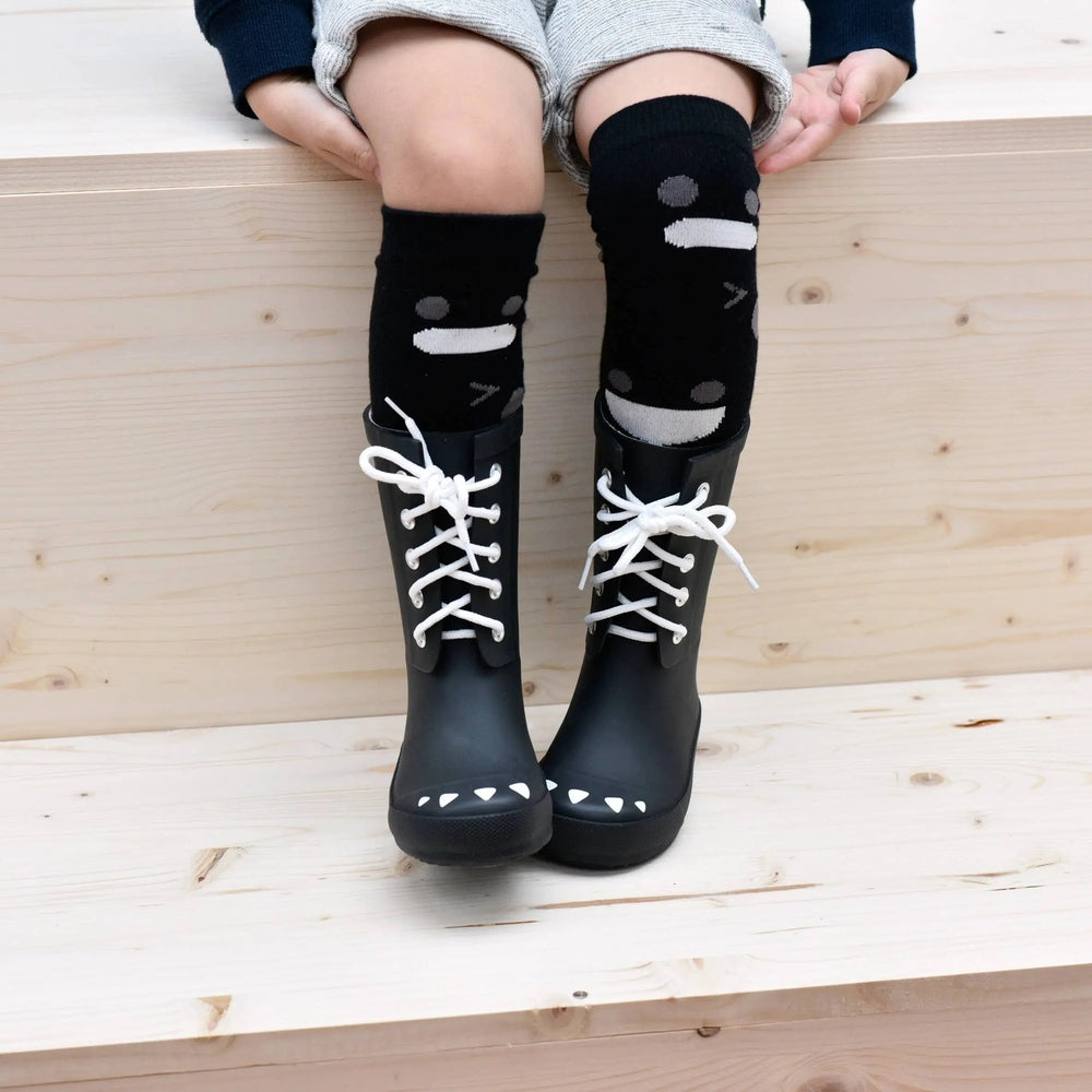 BOXBO Wistiti High Sock Black knee-high socks with white dot stripes worn by a child paired with lace-up boots.