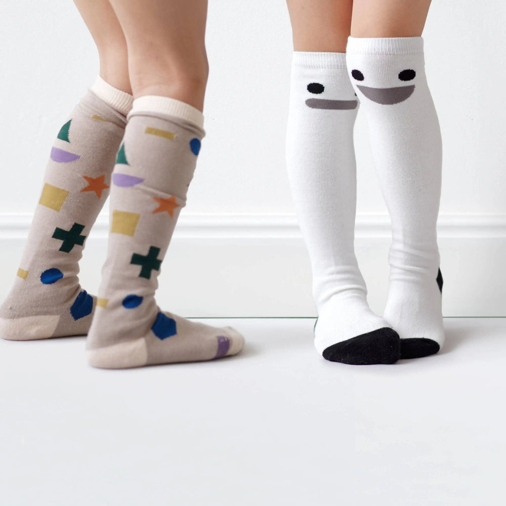 Boxbo Wistiti High Sock Blanc; white knee-highs with black toe tips paired with beige geometric socks on two kids, playful.