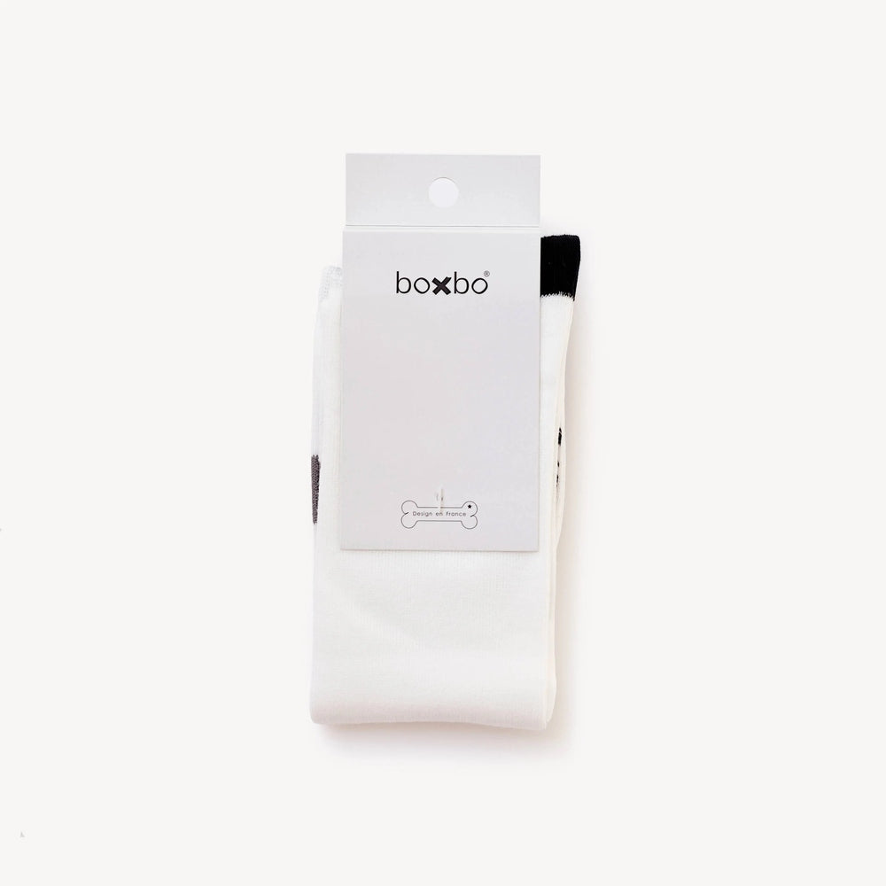 Boxbo Wistiti High Sock Blanc, white baby sock shown folded beside a tag to highlight its knit cotton length.