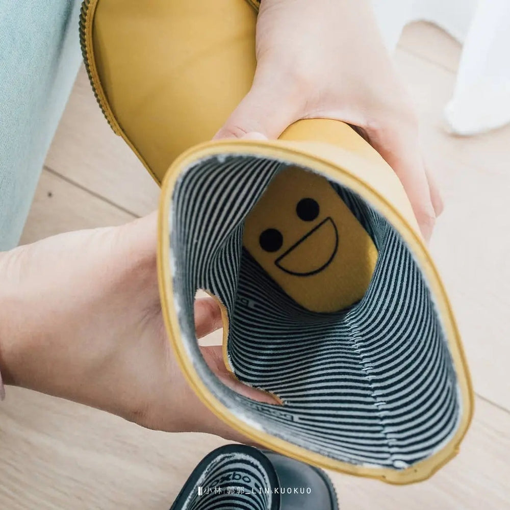 Boxbo Wistiti rainboots Moutarde held open to reveal striped blue lining and a smiley insole