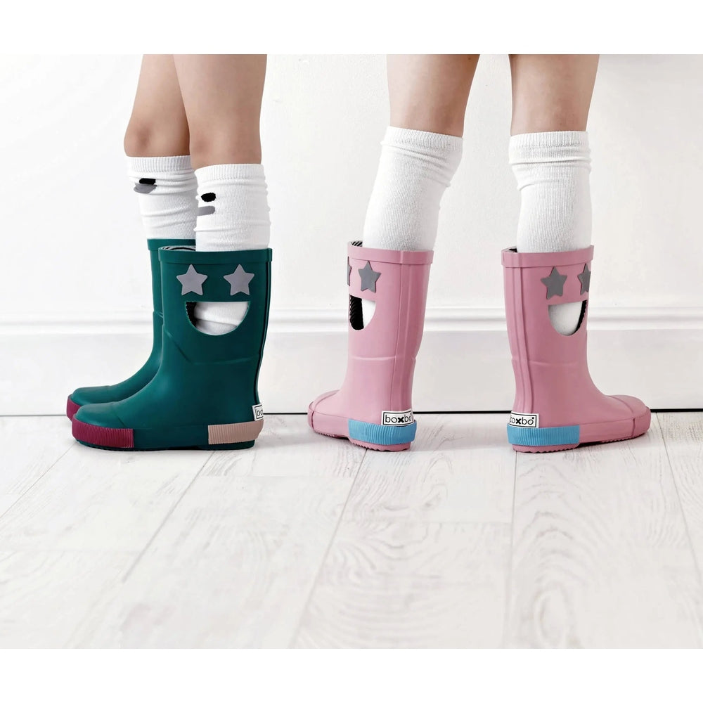 Boxbo Wistiti Rainboots Star Pink and teal kids' rubber boots with star cutouts, worn by children in white socks.