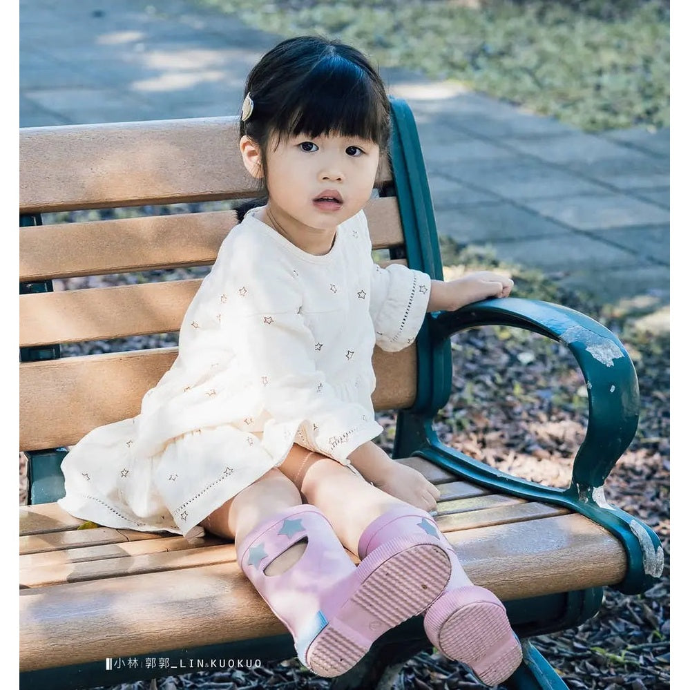 Boxbo Wistiti Rainboots Star Pink for toddlers; pink star-embellished rubber boots worn by a girl on a park bench