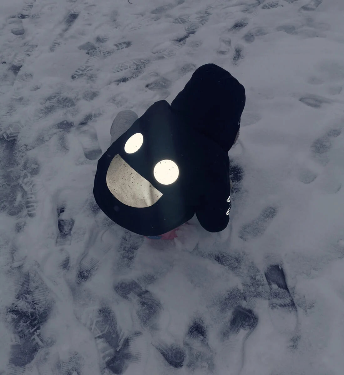 Black BOXBO Wistiti rain jacket outdoors in snow, with its smile design catching the light