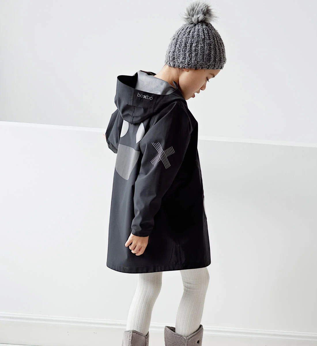 Child wearing the black BOXBO Wistiti rain jacket, back view with smile design