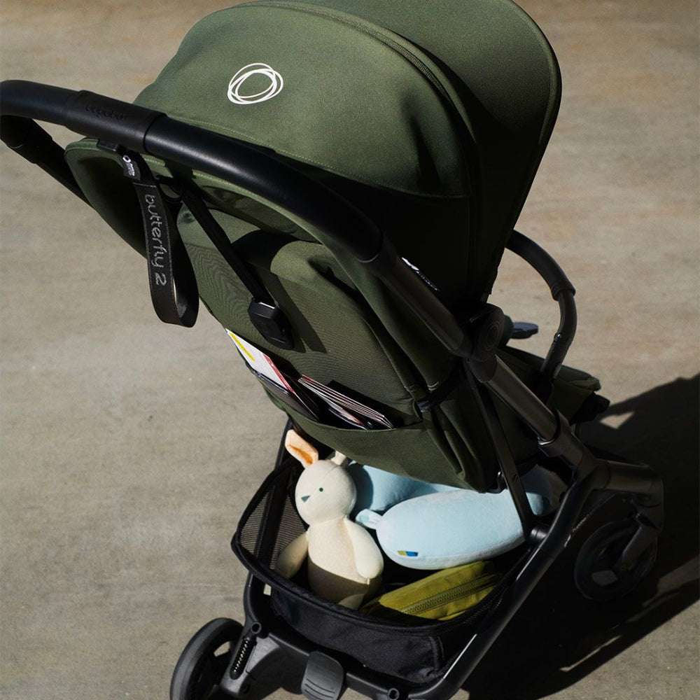Bugaboo Butterfly 2 stroller in olive green with accessories and a plush toy in the basket