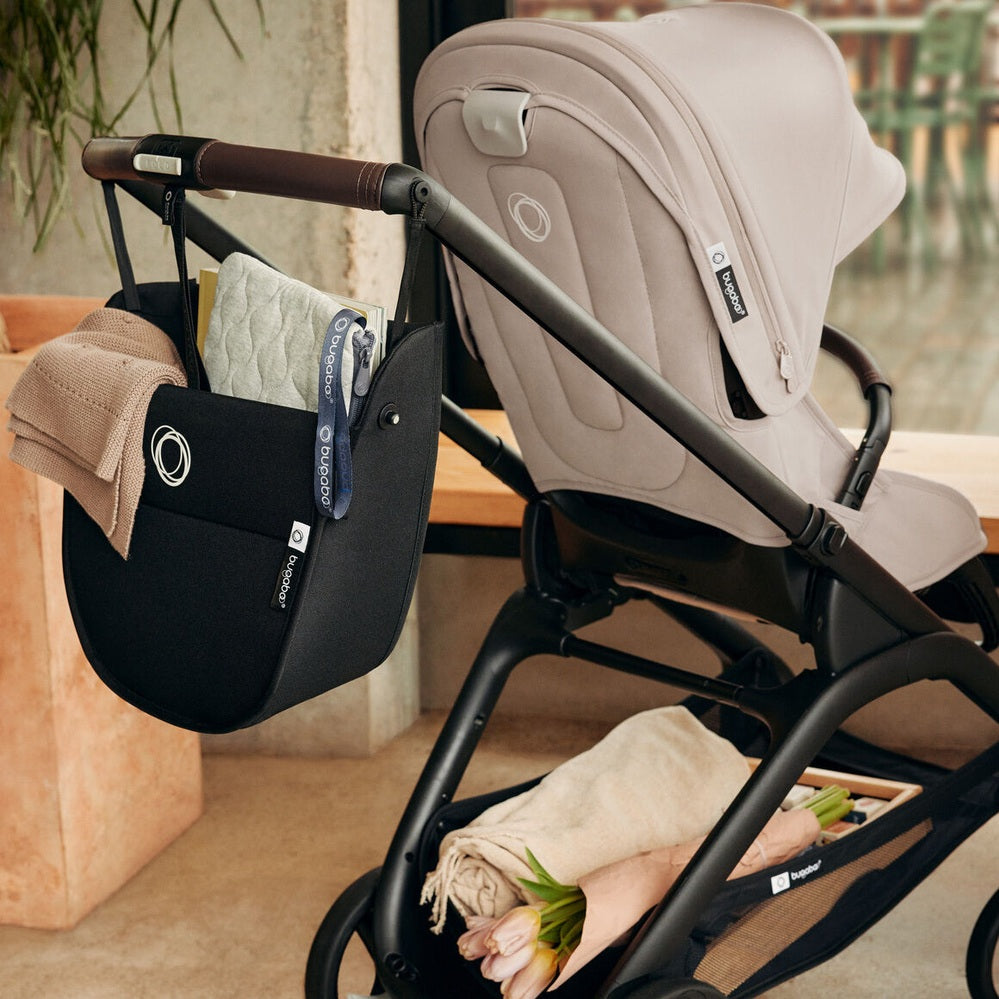 Bugaboo Dragonfly Stroller Complete in light gray, with a black storage bag hanging from the handle and a blanket.