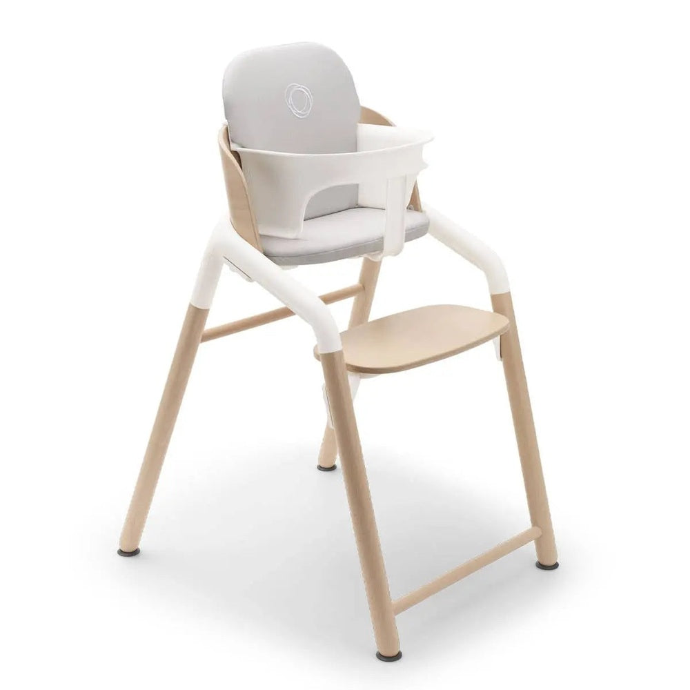 Bugaboo Giraffe Complete High Chair Set in natural wood and white with gray cushion, featuring a built-in tray and front safety bar.