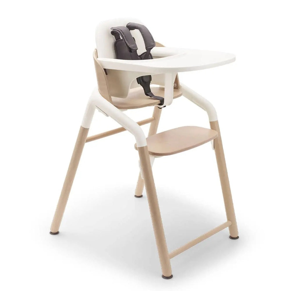 Bugaboo Giraffe Complete High Chair Set with white tray extended, beige wooden legs, and gray safety harness