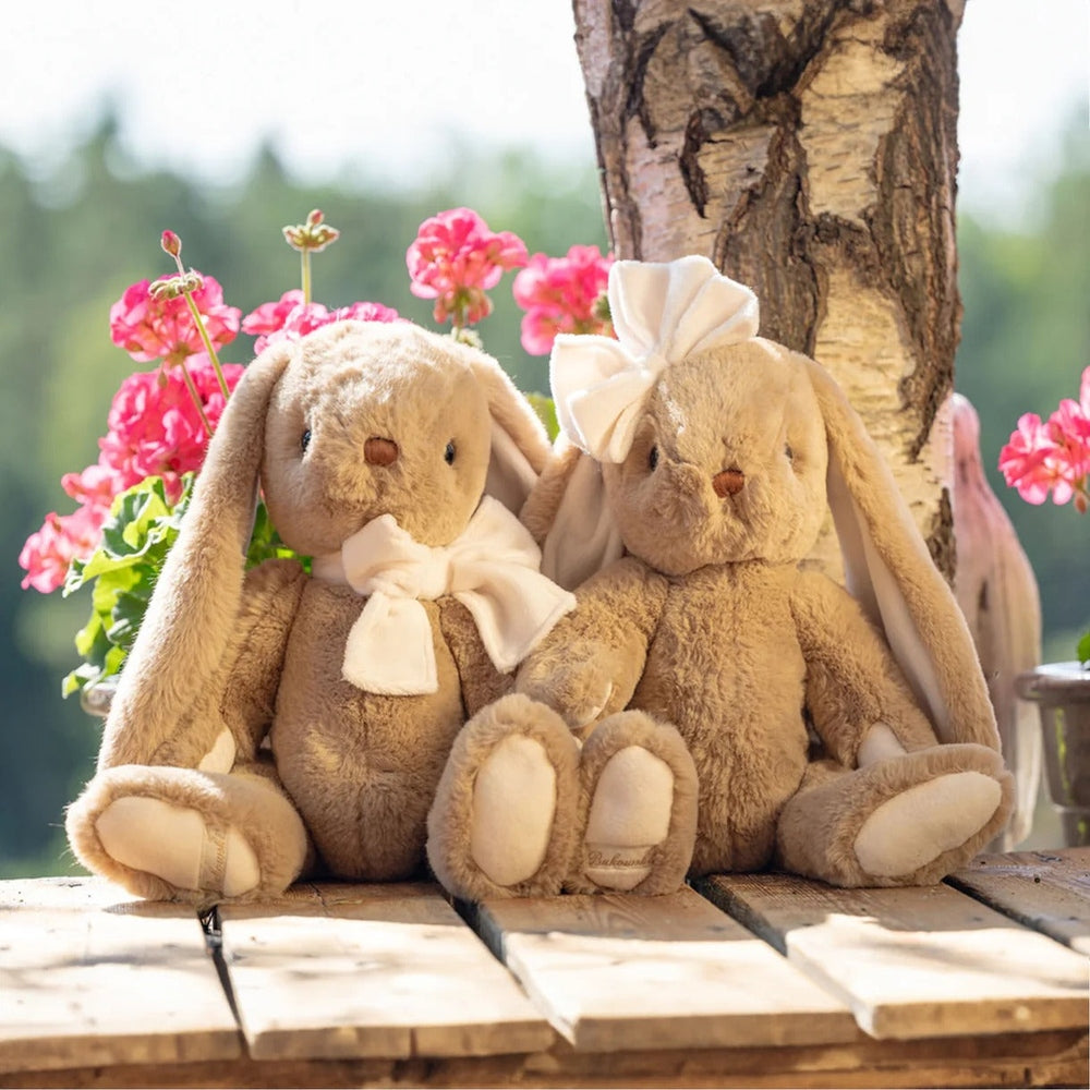 Bukowski Bears Gabrielle plush rabbits, tan/beige stuffed animals with white ribbons on a wooden surface