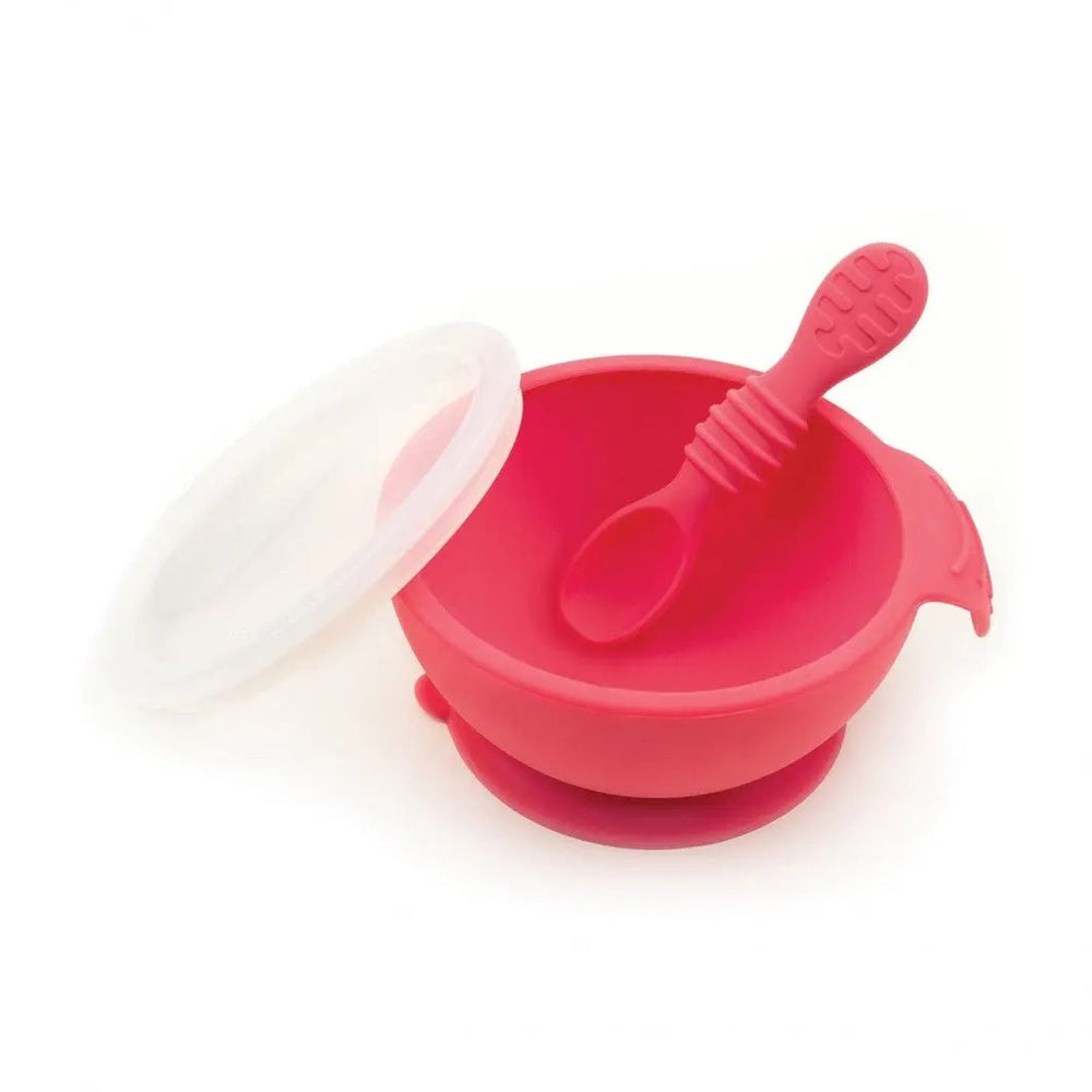 Bumkins Silicone First Feeding Set in pink, bowl with lid and textured spoon resting inside for easy baby feeding.