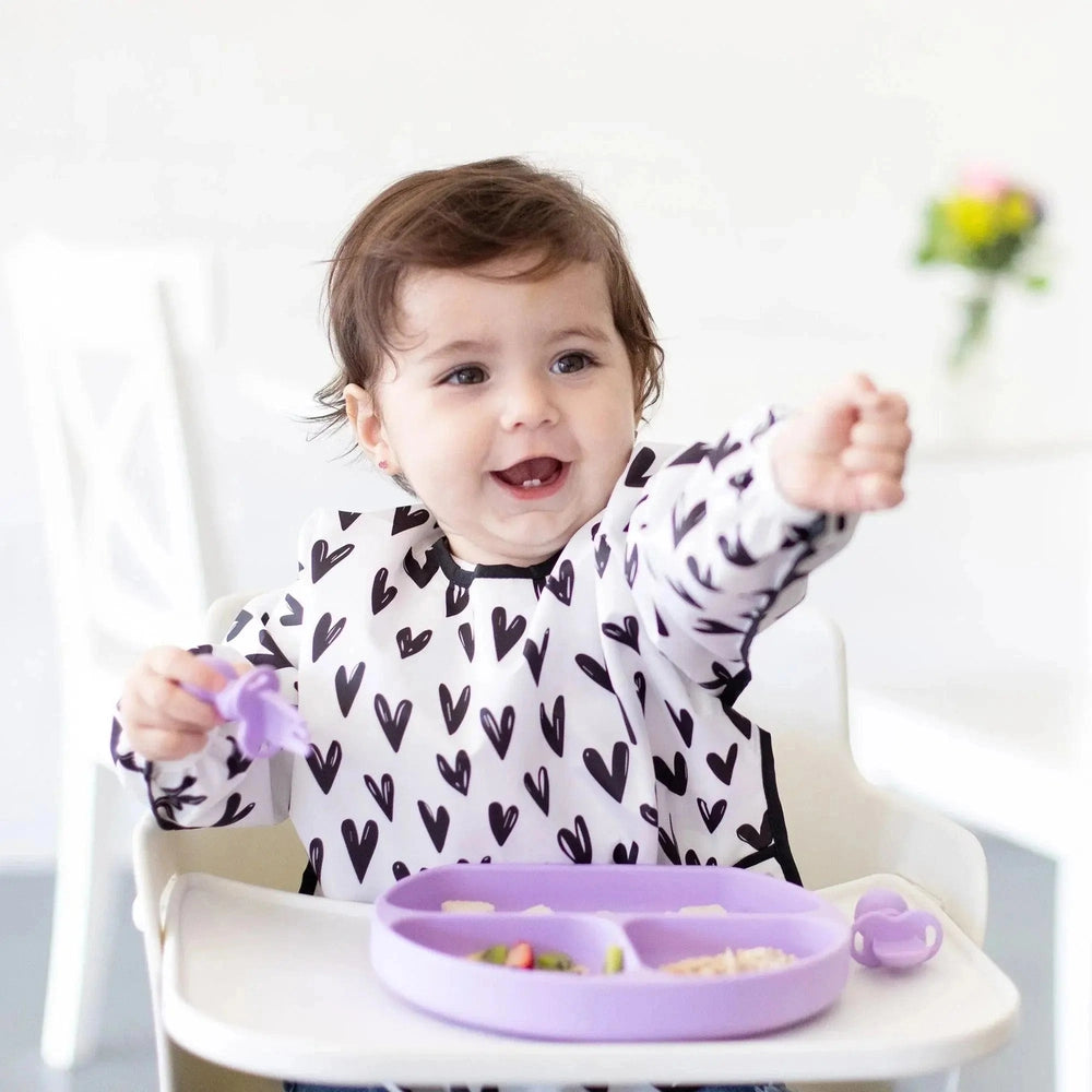 BUMKINS Silicone Grip Dish three-compartment purple plate with suction grip attached to tray as smiling baby eats.