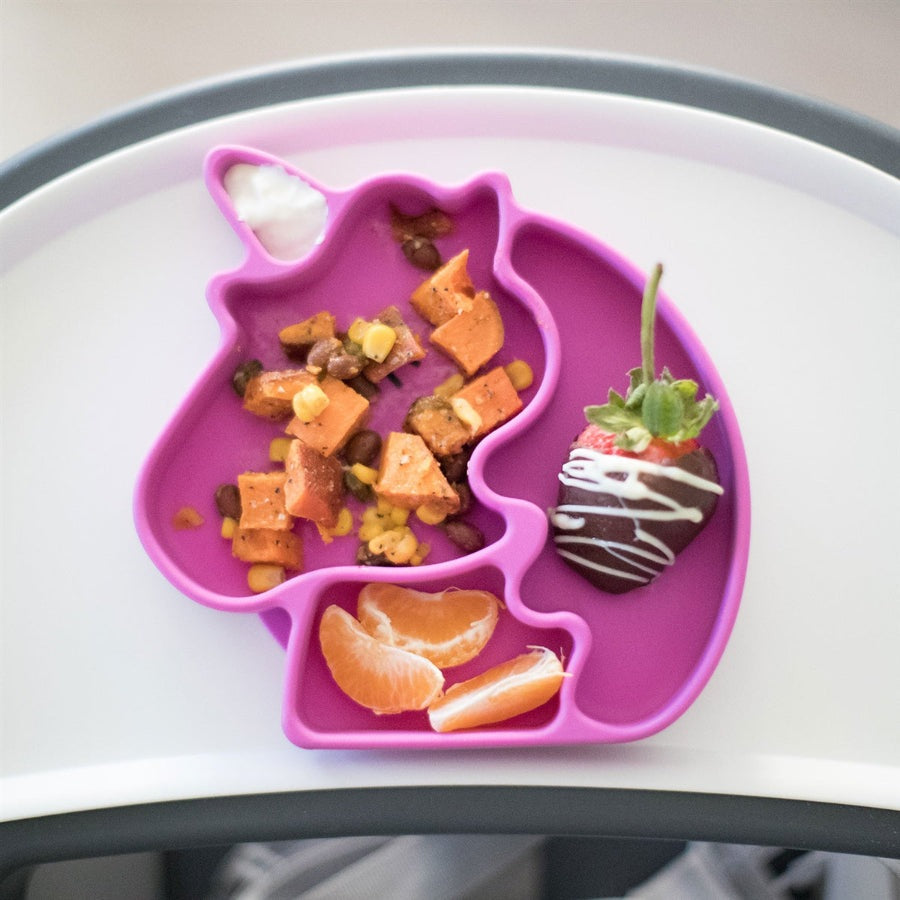 BUMKINS Silicone Grip Dish Unicorn in pink, unicorn-shaped plate with compartments holding orange bites and a chocolate-dipped strawberry