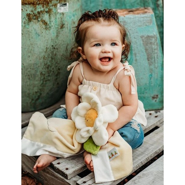 Bunnies By The Bay 16in Daisy Buddy Blanket plush toy with white petals and yellow center, held by a smiling baby