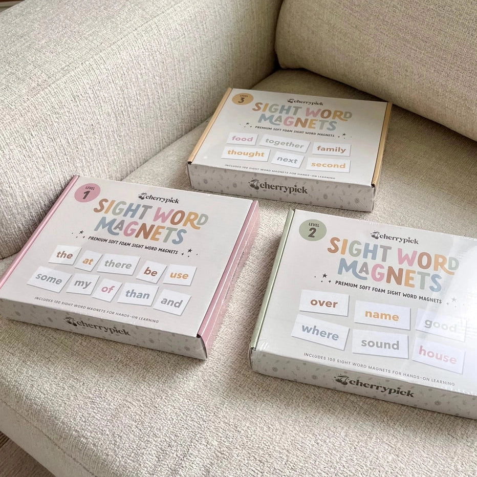 Cherrypick Sight Word Magnets in Pink, Green & Beige boxes on a sofa.
