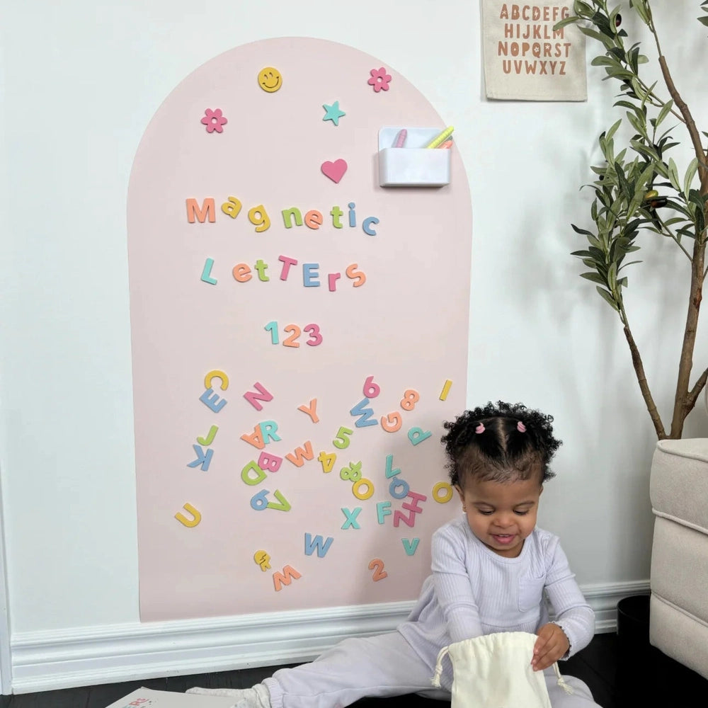 Cherrypick Soft Foam Magnetic Letters & Symbols 150pc Set in multicolor foam letters on pink arched wall board.