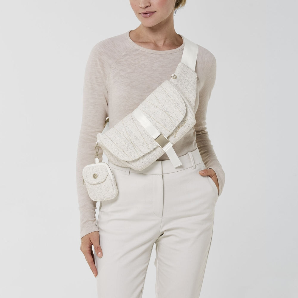 Close-up of the Cybex Belt Bag Boucle cream boucle belt bag worn crossbody with white strap and small attached pouch.
