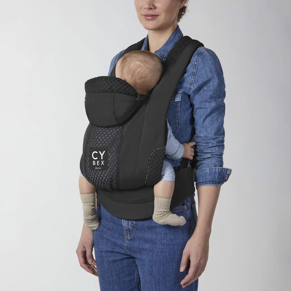 Close-up of the Cybex Coya Carrier in black with infant nestled inside; breathable mesh panels and padded straps.