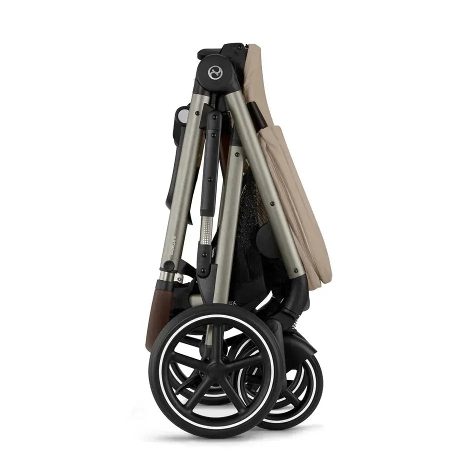 Close-up of the Cybex Gazelle S V2 Stroller folded compactly in beige fabric, silver frame, black wheels.