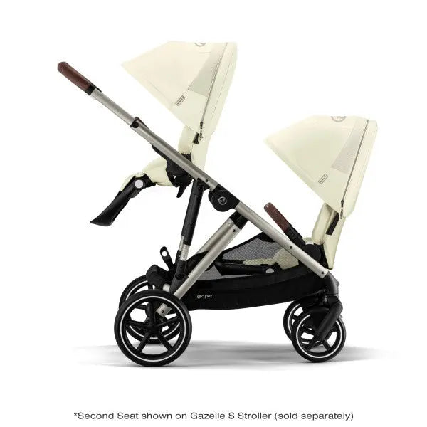 Close-up of the Cybex Gazelle S V2 Toddle Seat double stroller in cream with brown handles and upright canopies.