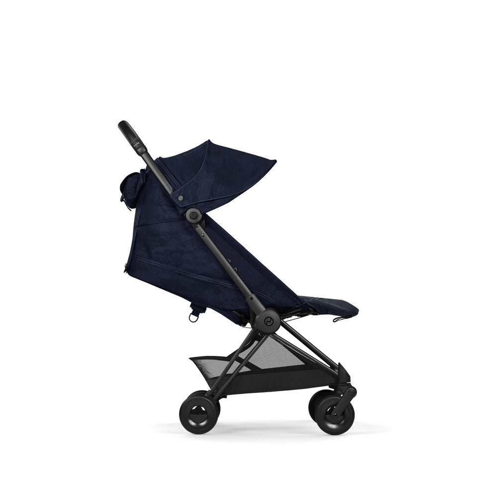 Close-up of the Cybex Platinum Coya Compact Lightweight Stroller - Rebellious Luxury Denim Blue in denim blue fabric with black frame and storage basket.