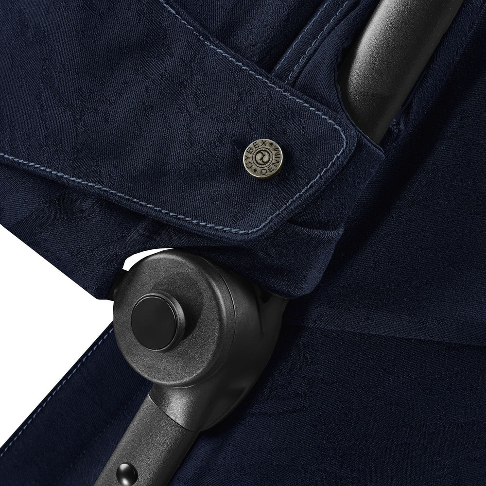 Close-up of the Cybex Platinum Coya Compact Lightweight Stroller - Rebellious Luxury Denim Blue navy denim-blue cybex coya compact stroller fabric with contrast stitching and black hinge.