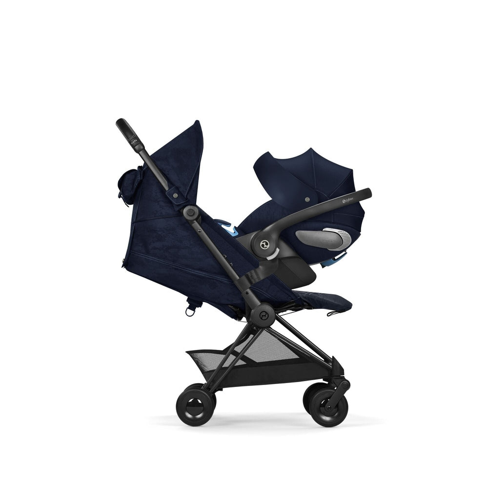 Close-up of the Cybex Platinum Coya Compact Lightweight Stroller - Rebellious Luxury Denim Blue with black frame, extended canopy, and under-seat mesh basket.