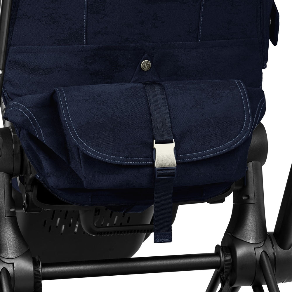 Close-up of the Cybex Platinum e-Priam 4 Stroller Limited Edition - Rebellious Luxury Denim Blue denim-blue canvas storage pouch on cybex e-priam stroller, navy fabric with light stitching and silver buckle.