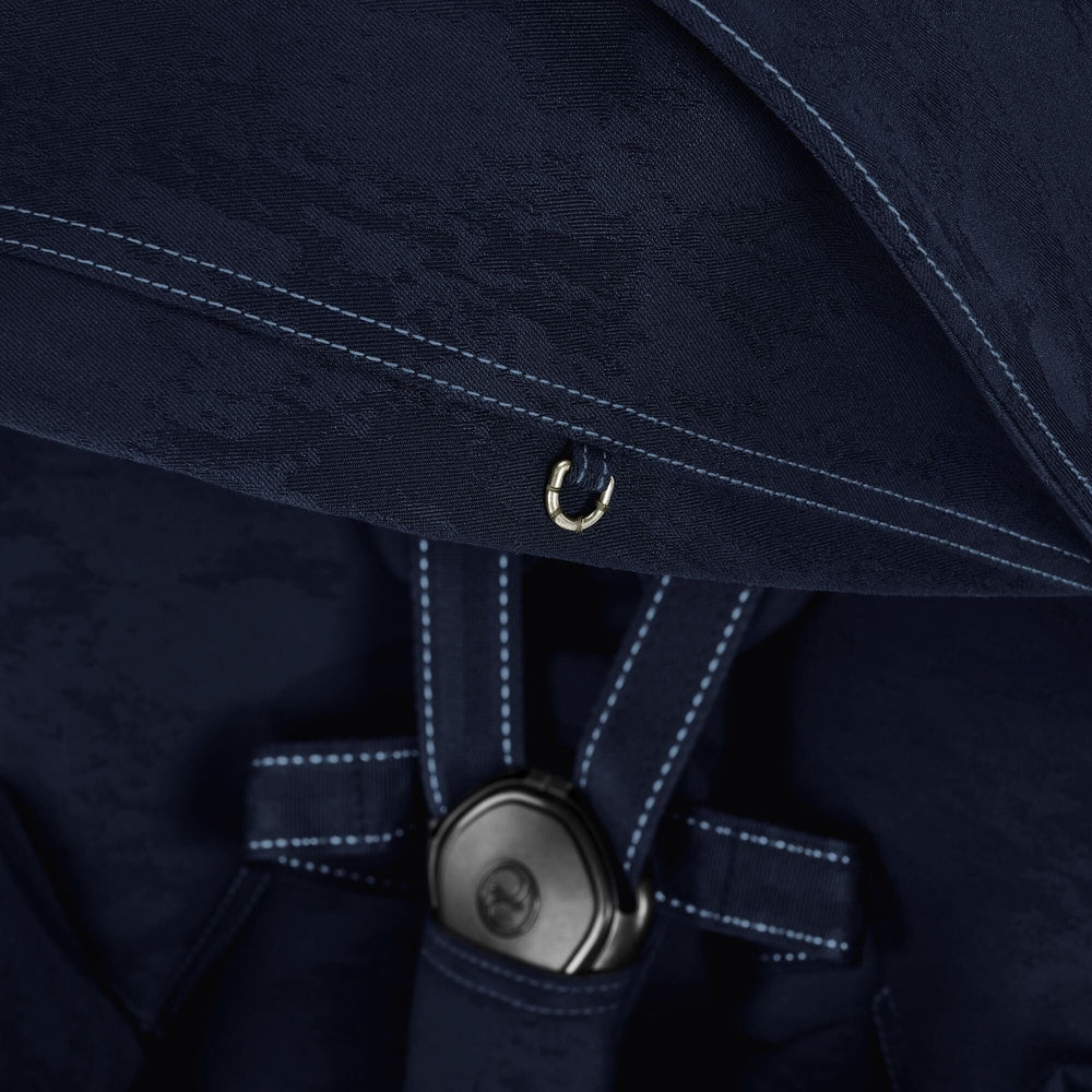 Close-up of the Cybex Platinum Mios 3 Stroller Rebellious Luxury Denim Blue navy blue MIOS stroller fabric with denim-like texture, light blue contrast stitching, and metal ring detail.