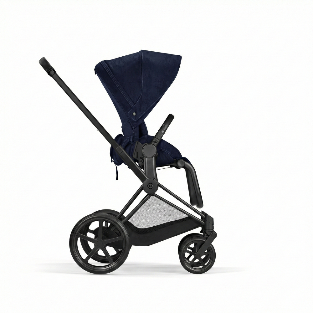 Close-up of the Cybex Platinum Priam 4 Stroller Limited Edition - Rebellious Luxury Denim Blue in denim blue fabric with navy canopy, black frame, large rear wheels and mesh underbasket.