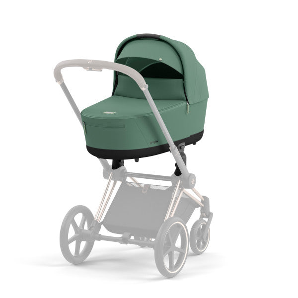 Close-up of the Cybex Platinum Priam Lux Carry Cot atop a silver stroller frame with green fabric and canopy.