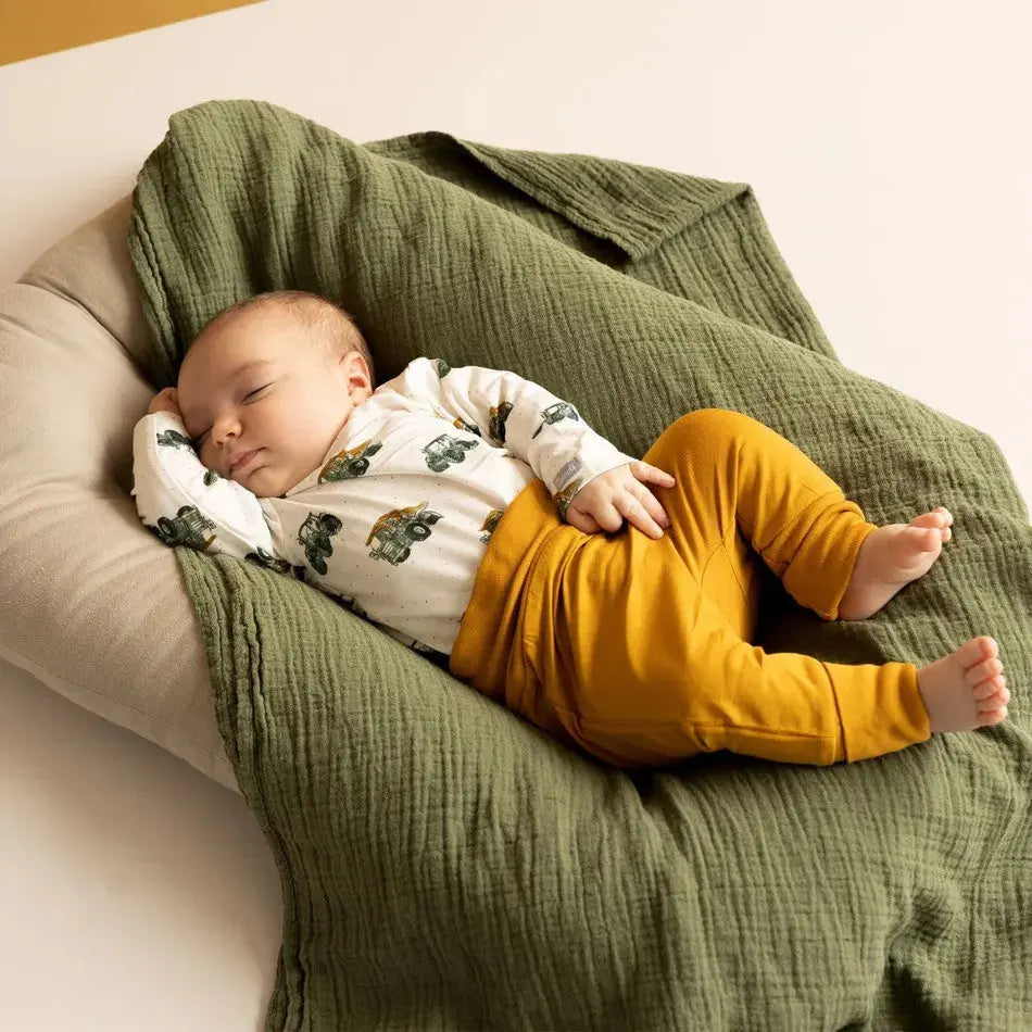 Coccoli Infant Cotton TENCELTM Modal Romper Cream Tractors; sleeping baby in cream romper with tractor print on a green knit blanket