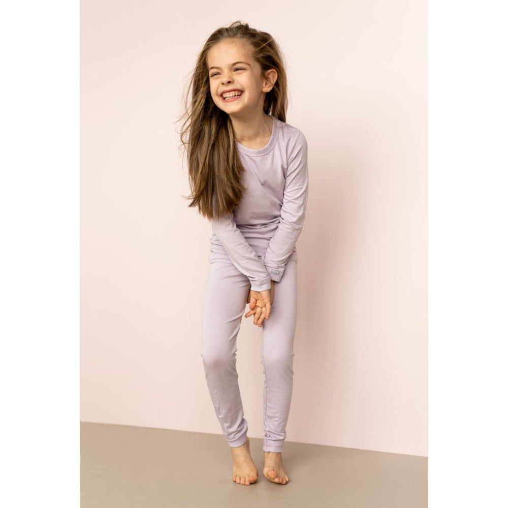 Coccoli Kid Long Sleeve Cotton TENCELTM Modal Pajamas in lavender fog; smiling girl models them barefoot.