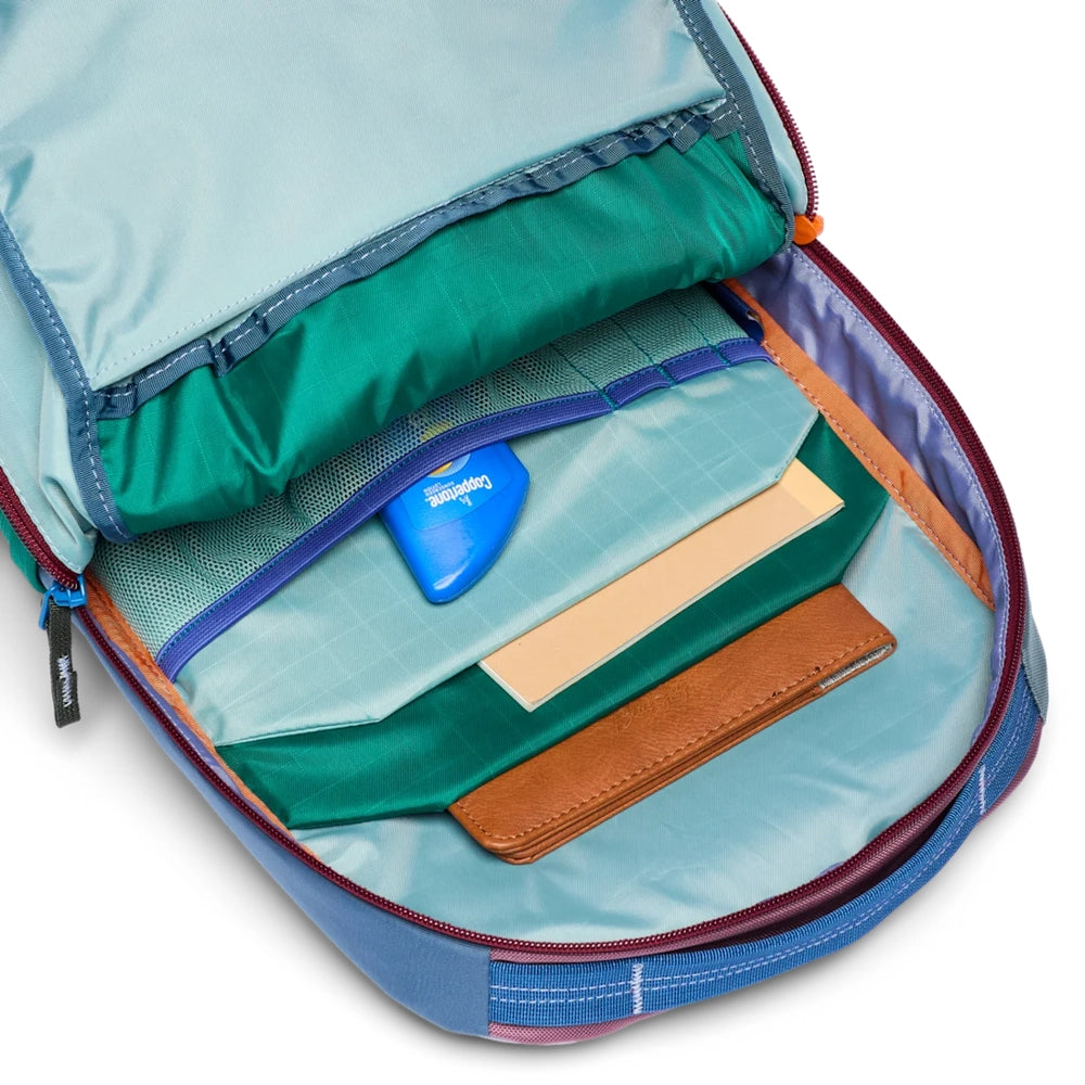 Cotopaxi Allpa 18L Daypack interior in teal lining with turquoise pockets, orange zipper, tan leather wallet and notebook.