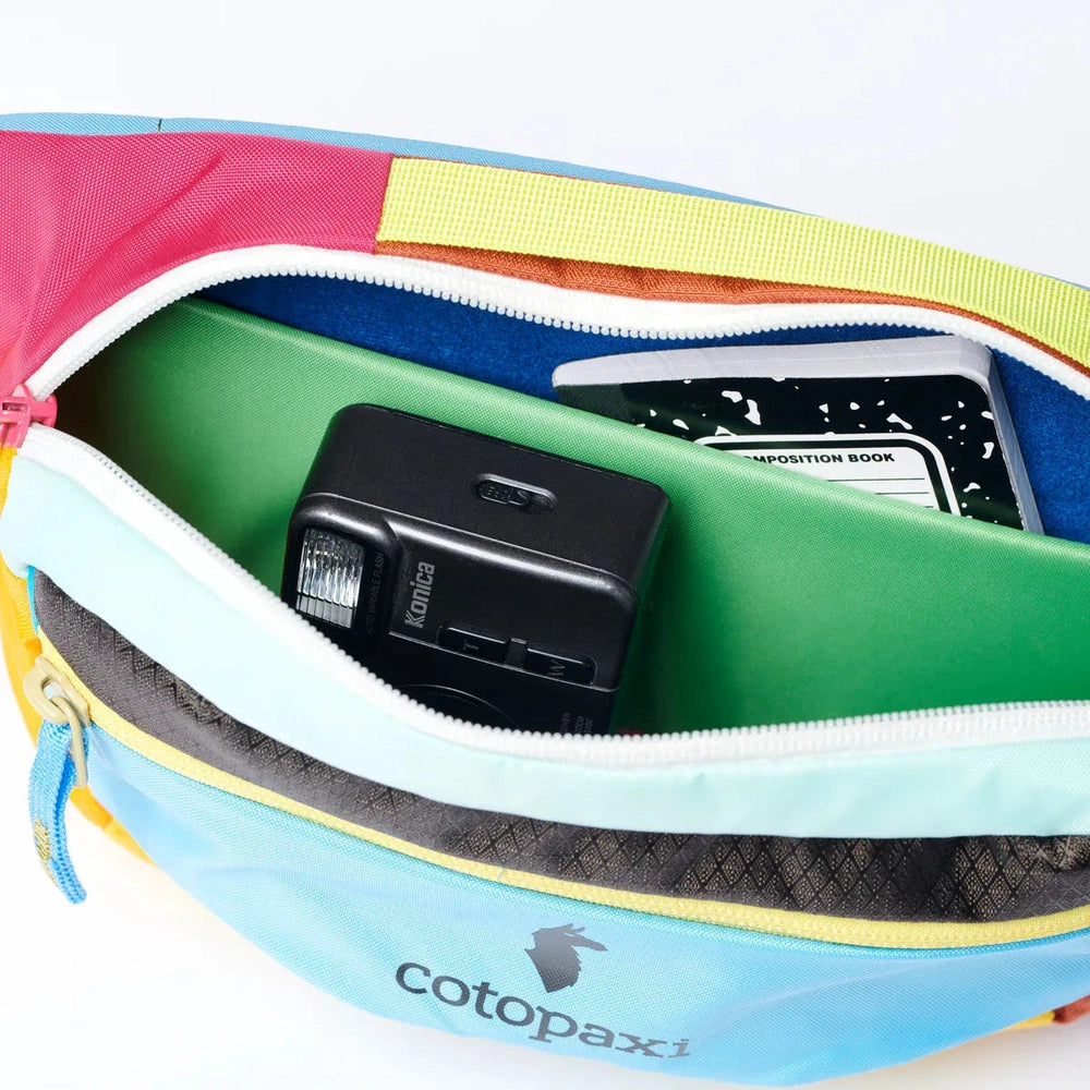 Colorful zippered pouch with electronic device and book inside, featuring Cotopaxi branding.