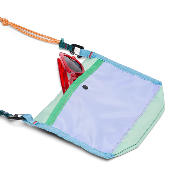 Cotopaxi Lista 2L Crossbody Bag in light blue with mint green panels and turquoise strap, sunglasses tucked inside.