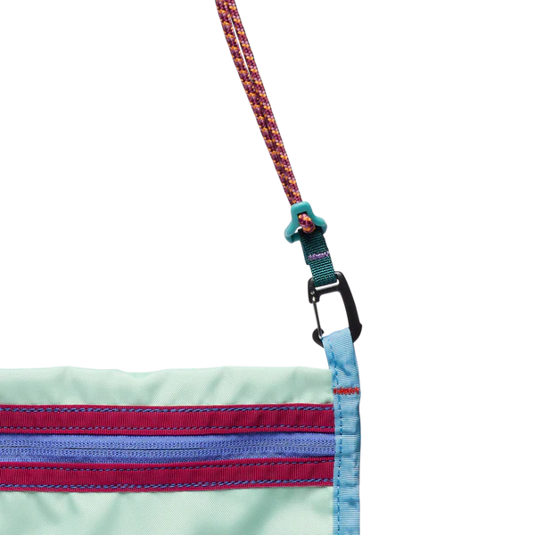 Cotopaxi Lista 2L Crossbody Bag in Mint Green with purple zipper accents and teal hardware, rainbow woven strap.