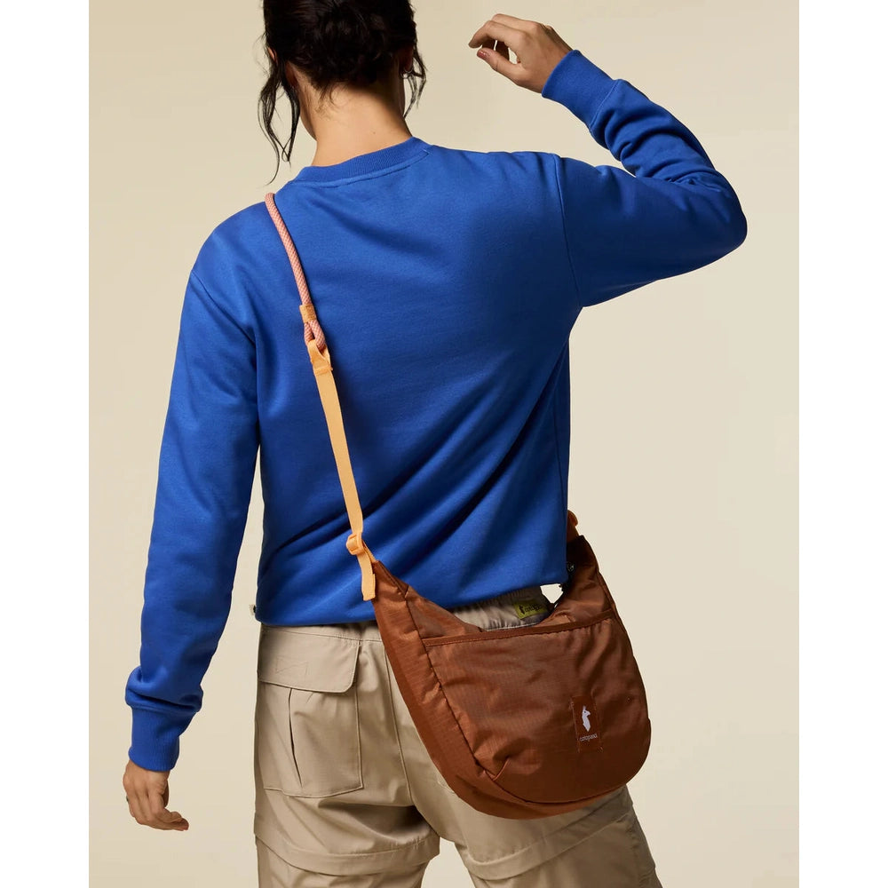 Cotopaxi Trozo 8L Shoulder Bag Cada Dia in brown with peach strap worn crossbody