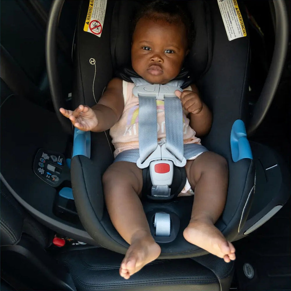 Close-up of the Cybex Aton G Swivel Sensorsafe Infant Car Seat ; baby buckled into gray harness with blue accents, seated securely.