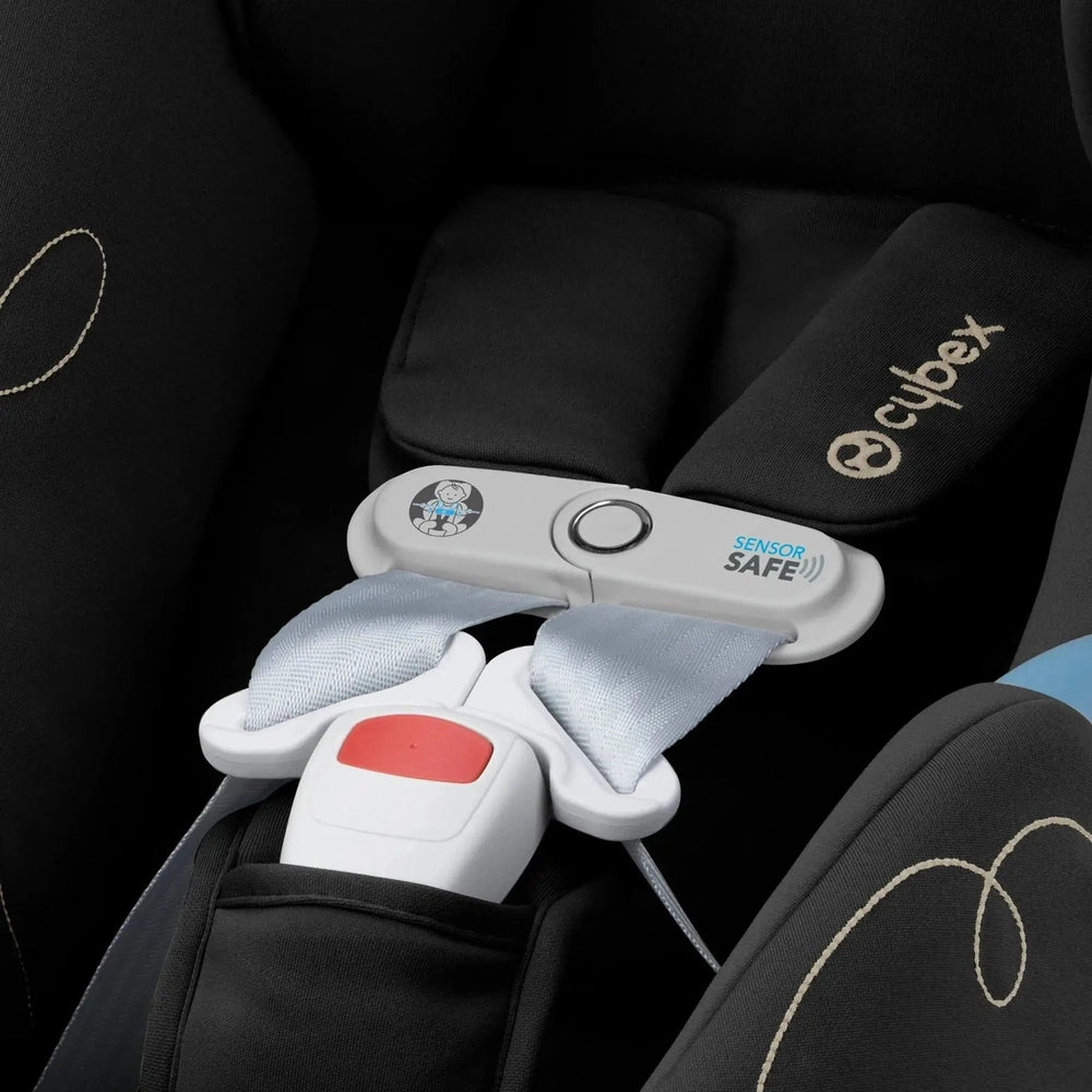Close-up of the Cybex Aton G Swivel Sensorsafe Infant Car Seat in black fabric with a buckled red harness.