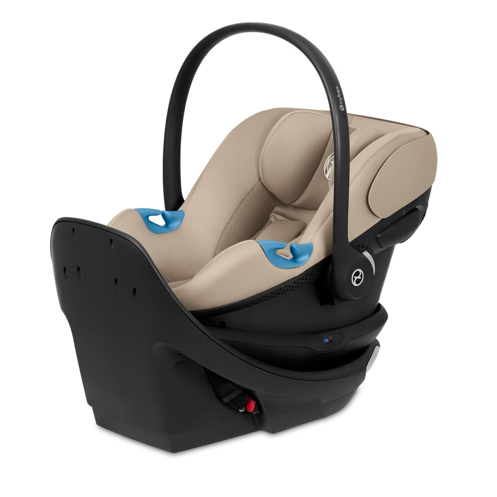 Close-up of the Cybex Aton G Swivel Sensorsafe Infant Car Seat beige fabric infant car seat with black base and curved arch handle; blue harness buckles.