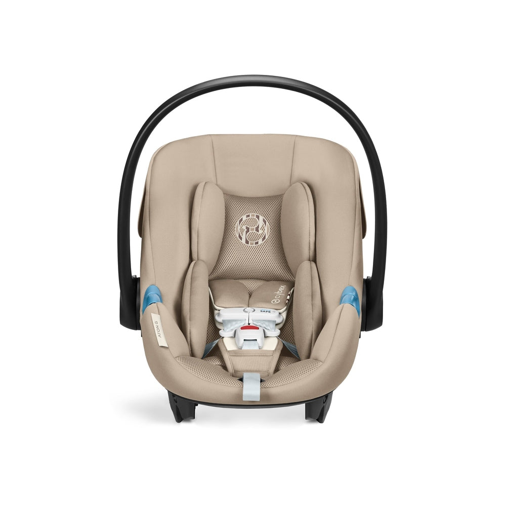 Close-up of the Cybex Aton G Swivel Sensorsafe Infant Car Seat beige fabric infant car seat with black curved handle, padded mesh head support, five-point harness.